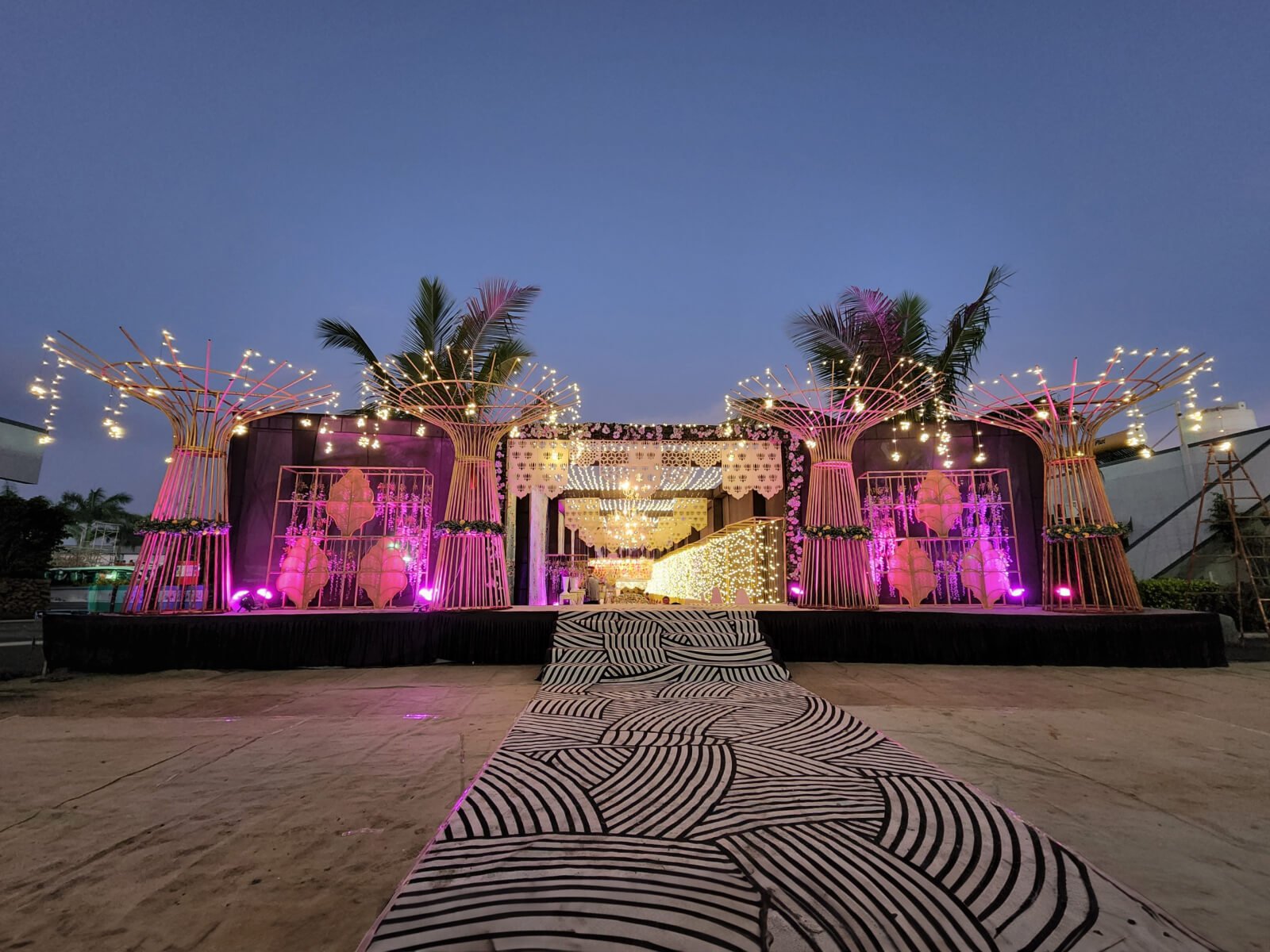 Indoor event Entrance corridor with floral decorations, hanging lights, and patterned walkway, ideal for wedding receptions and special celebrations.