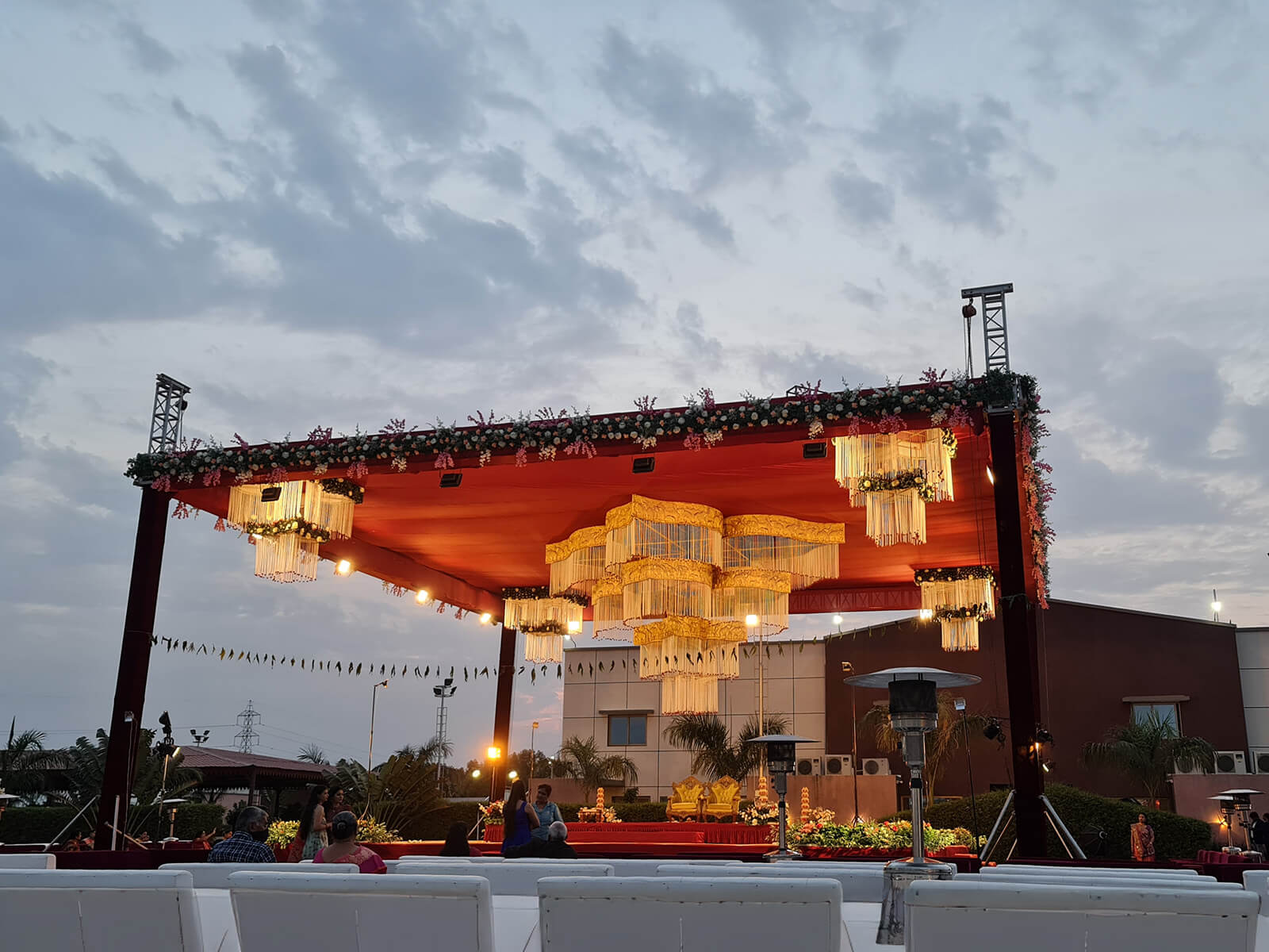 Outdoor wedding stage with floral decorations and elegant lighting, perfect for evening wedding ceremonies and special events.