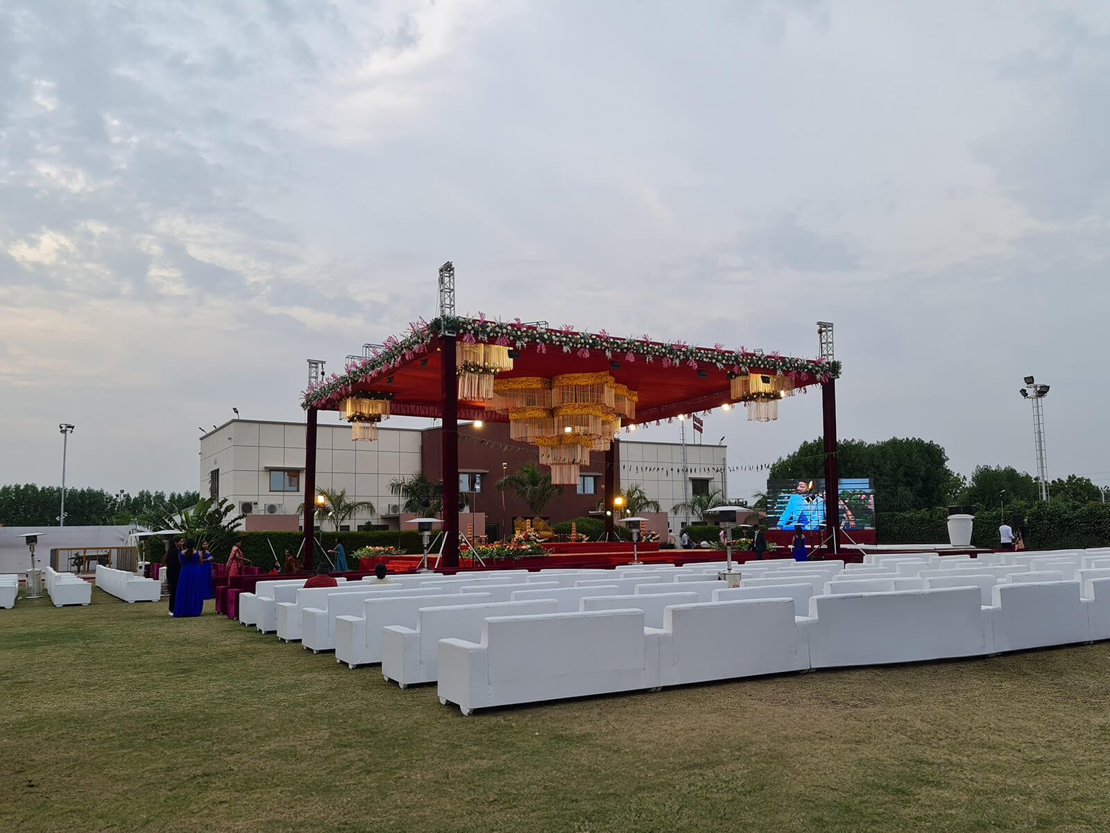 Outdoor event canopy with red and white drapes, floral decorations, and elegant seating arrangement, ideal for wedding ceremonies and special celebrations.