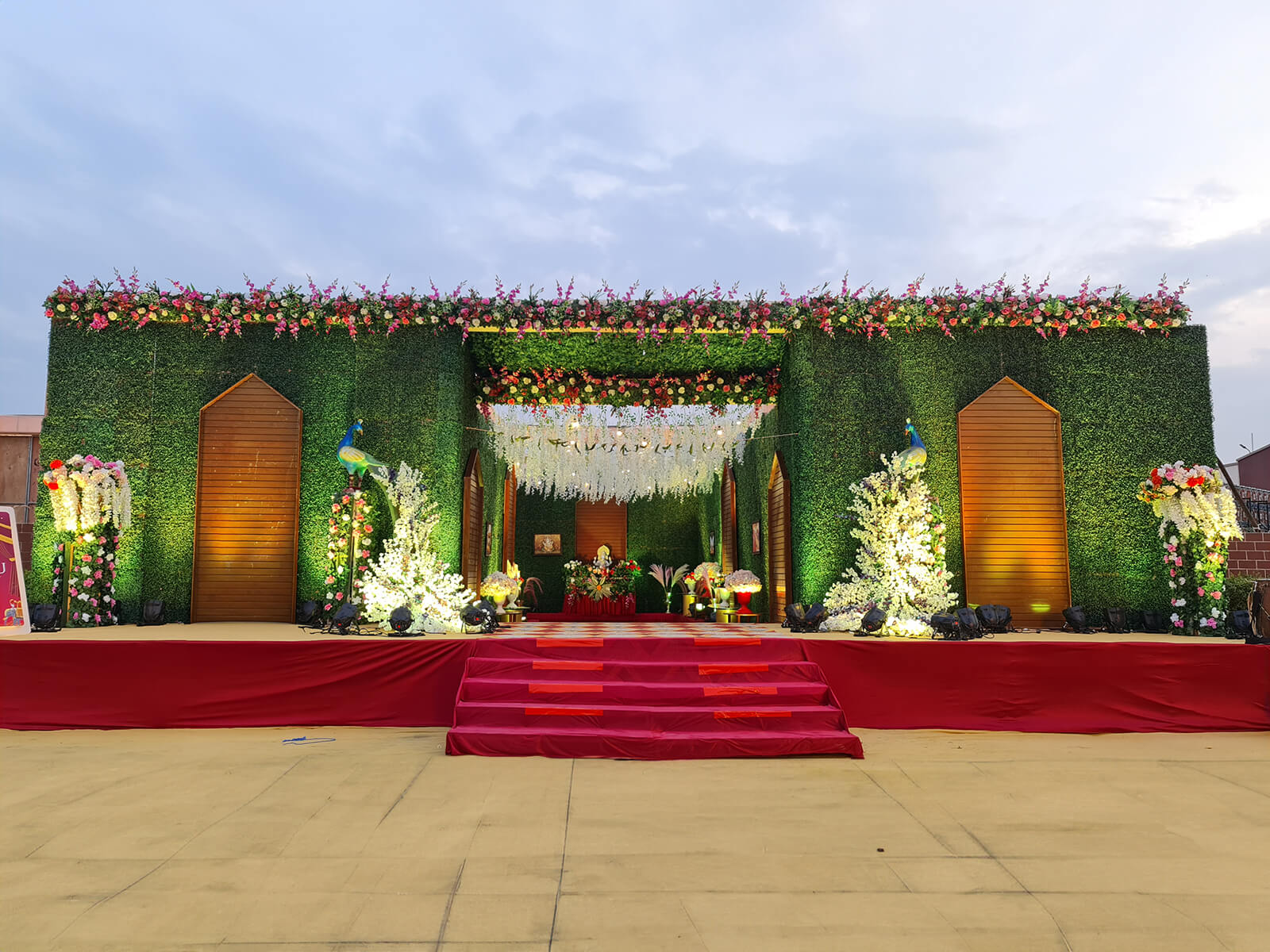 Outdoor wedding stage with lush greenery and floral decorations, perfect for wedding ceremonies and special events.