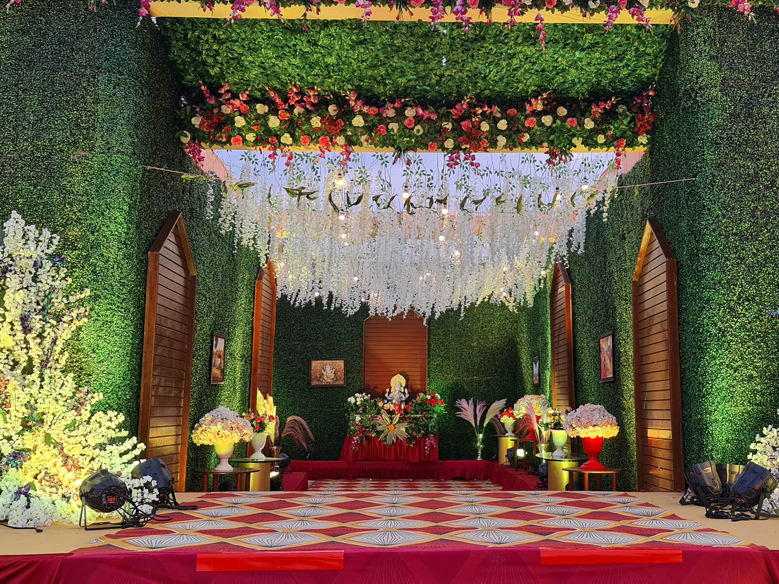 Indoor event space with elegant floral decorations and hanging lights, ideal for special occasions and celebrations.