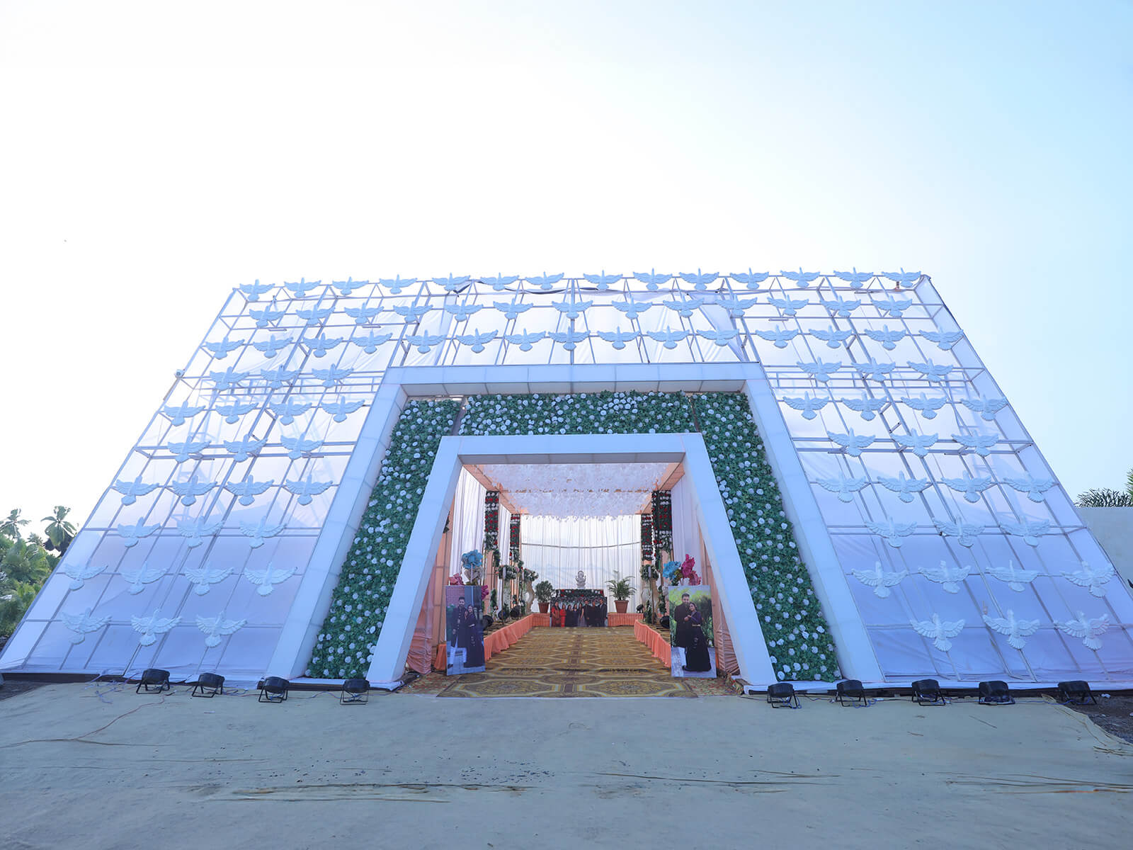 Entrance to a beautifully decorated wedding hall with floral arrangements and a unique geometric archway, perfect for welcoming guests to special events and ceremonies.