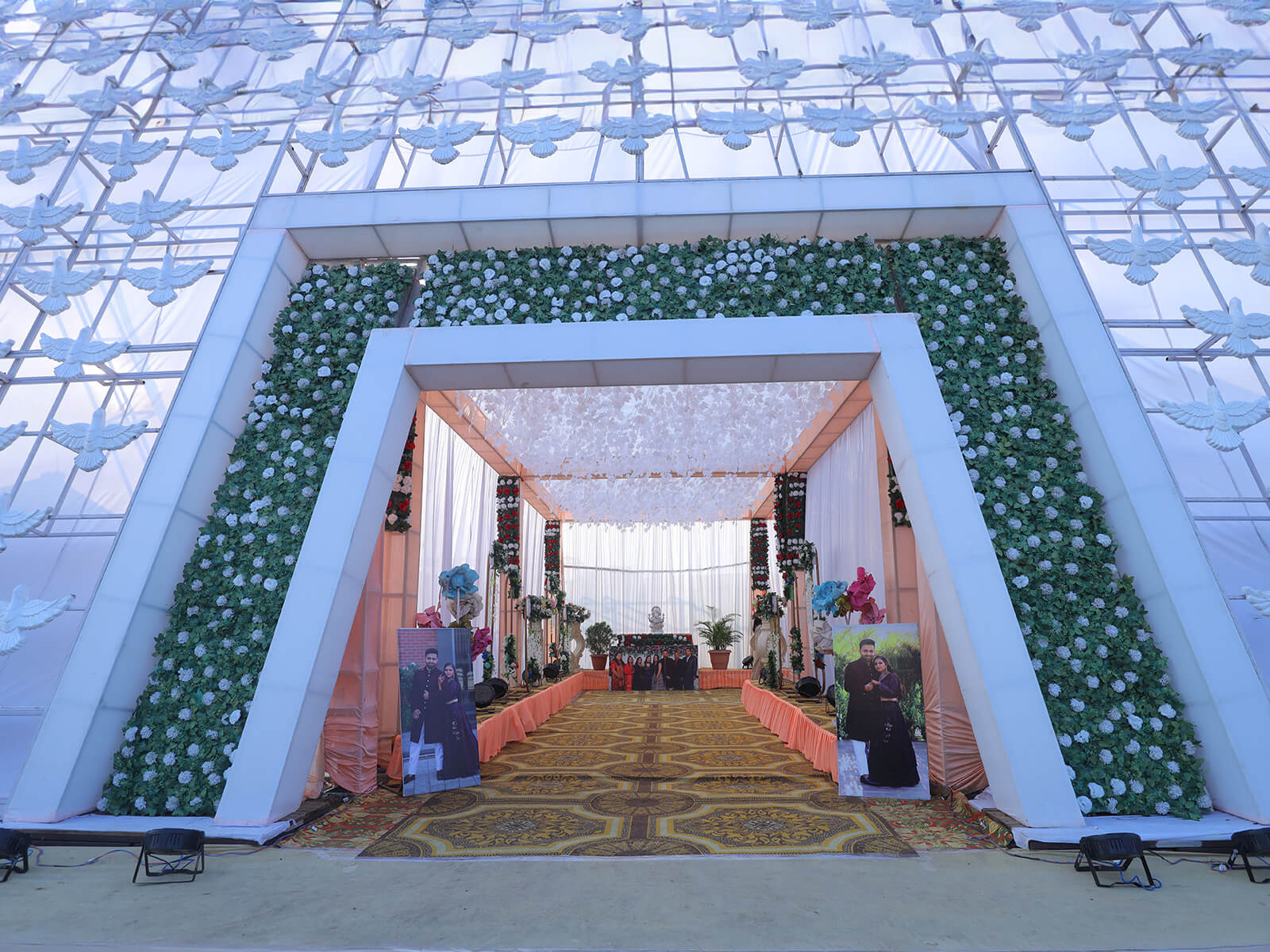 Entrance to a beautifully decorated wedding hall with floral arrangements and a unique geometric archway, perfect for welcoming guests to special events and ceremonies.