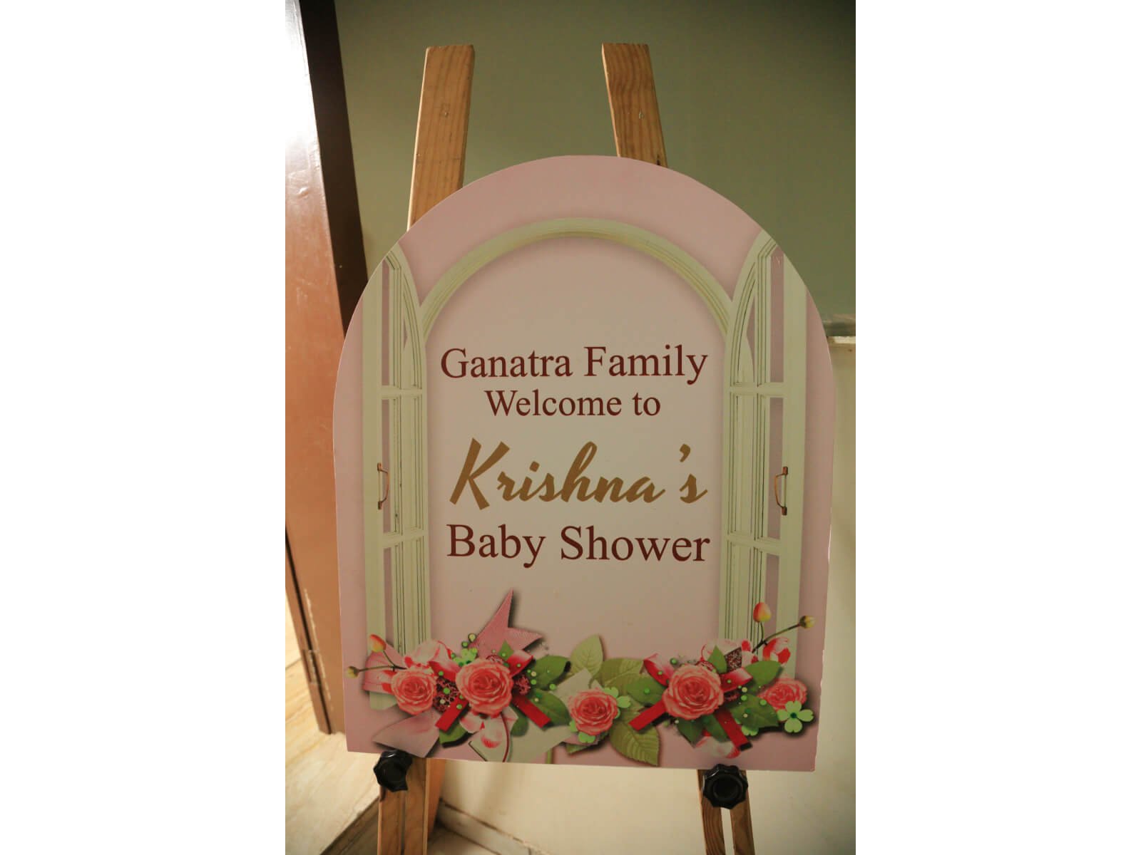 Indoor baby shower welcome sign with floral decorations and pastel colors.