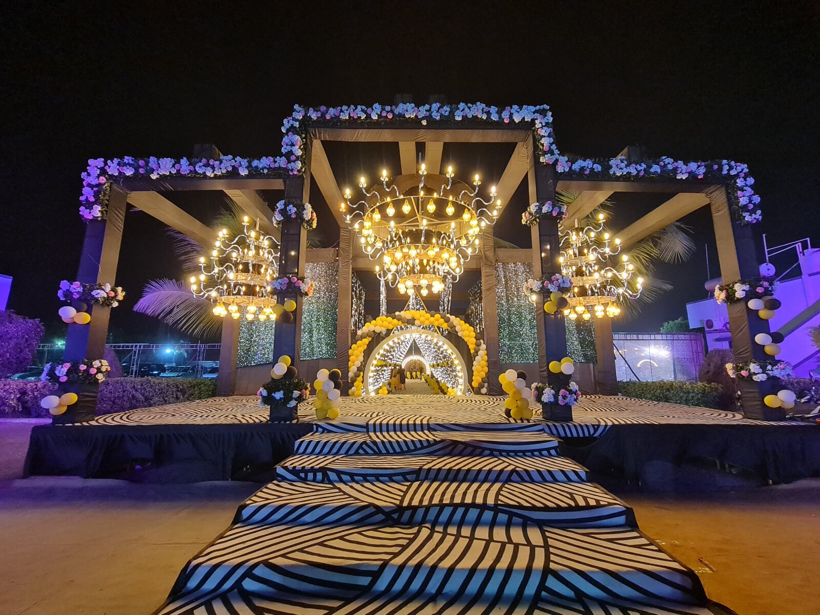 Outdoor wedding event with grand illuminated chandeliers and floral decorations, ideal for wedding decoration, event planning, and destination weddings.