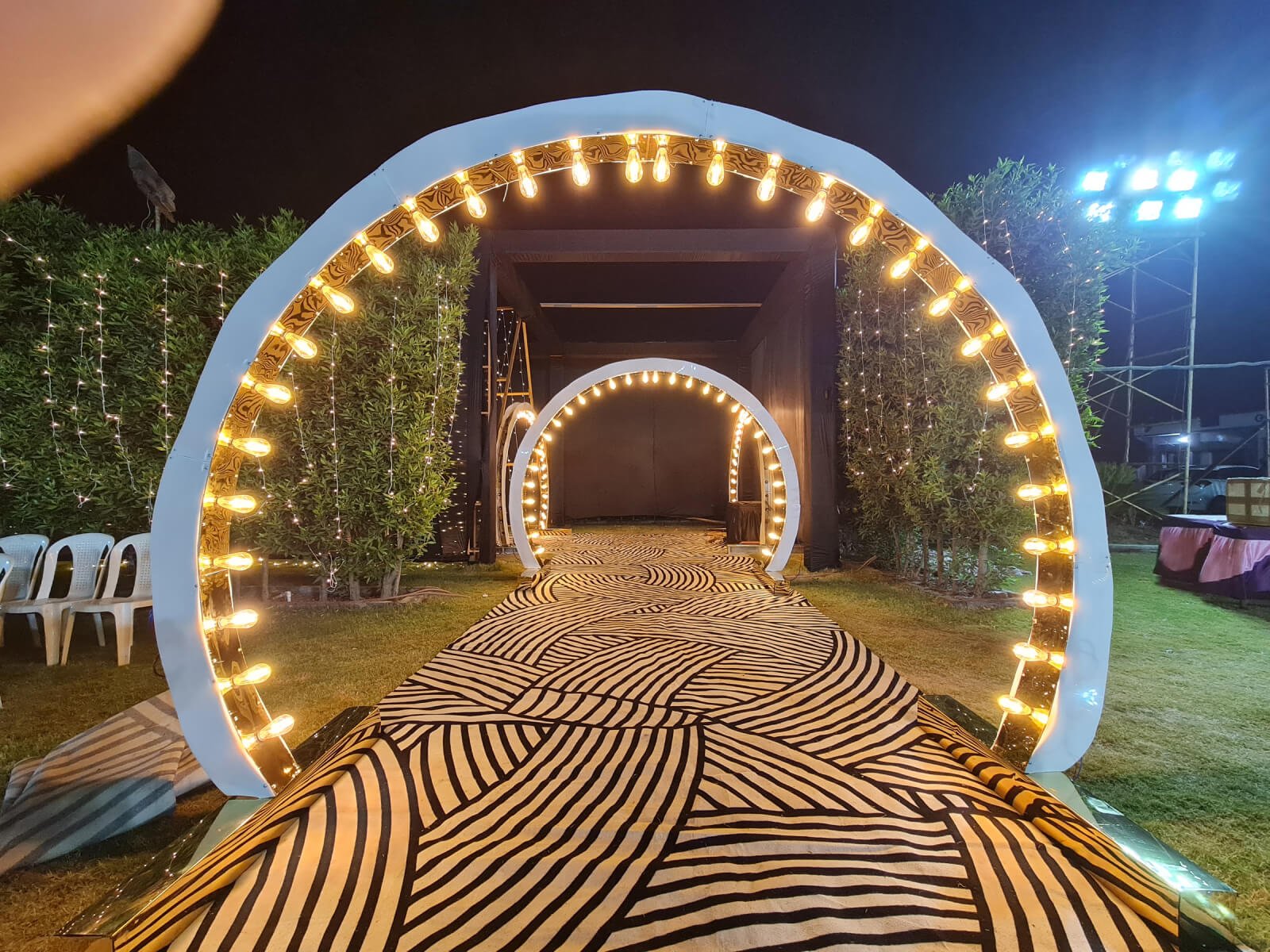 Outdoor wedding event entrance with illuminated arches and decorative pathway, ideal for wedding decoration, event planning, and destination weddings.