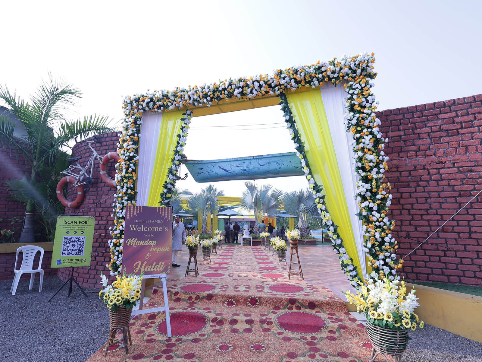 Outdoor Haldi event decoration with vibrant yellow drapes, colorful floral arrangements, and traditional seating, ideal for wedding celebrations and event planning.