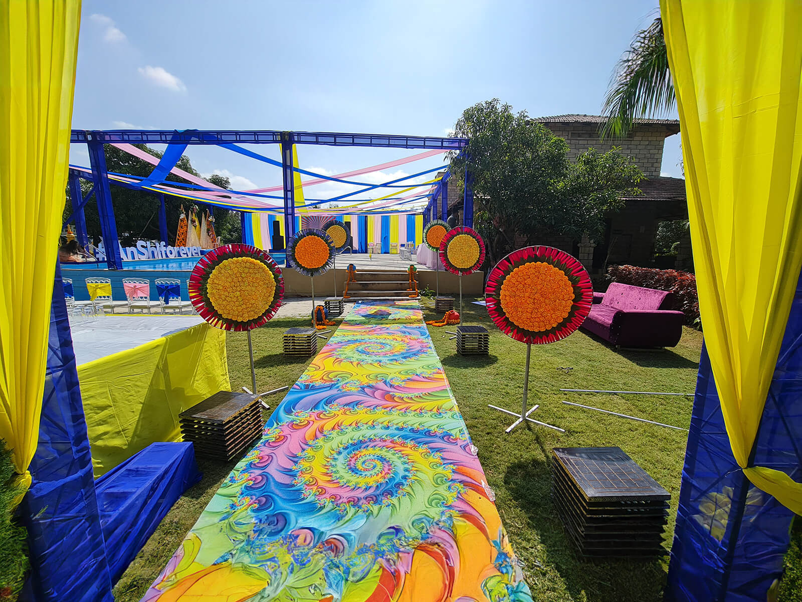 Outdoor event setup with vibrant decorations and colorful pathway, perfect for wedding decoration, event planning, and sangeet ceremonies.