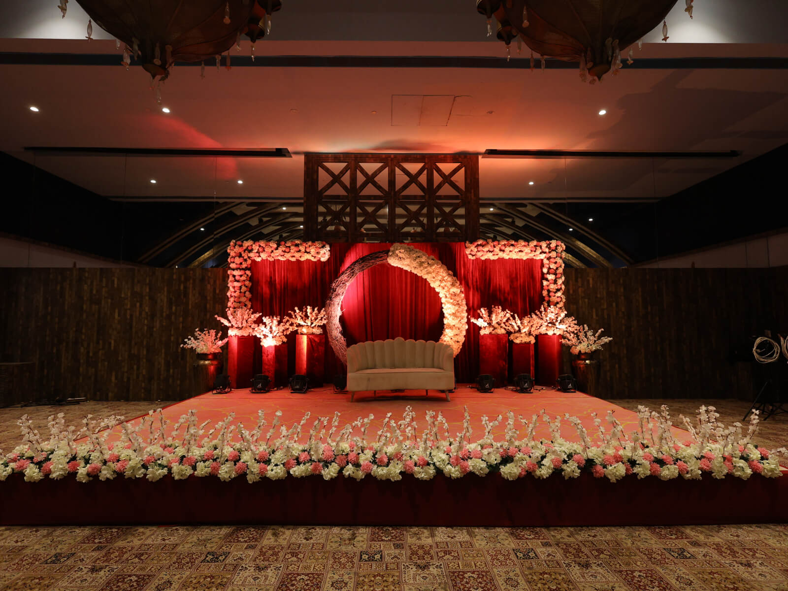 Indoor wedding event stage with floral decorations and elegant backdrop, perfect for wedding decoration, event planning, and anniversary celebrations.