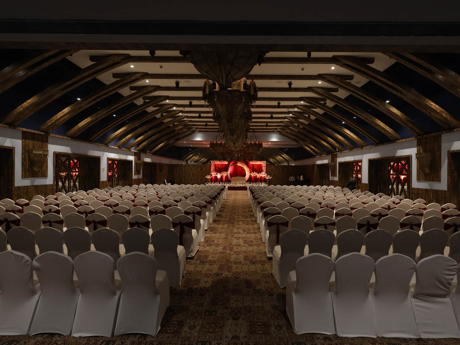 Indoor wedding event hall with elegant seating arrangement and stage setup, perfect for wedding decoration, event planning, and sangeet ceremonies.