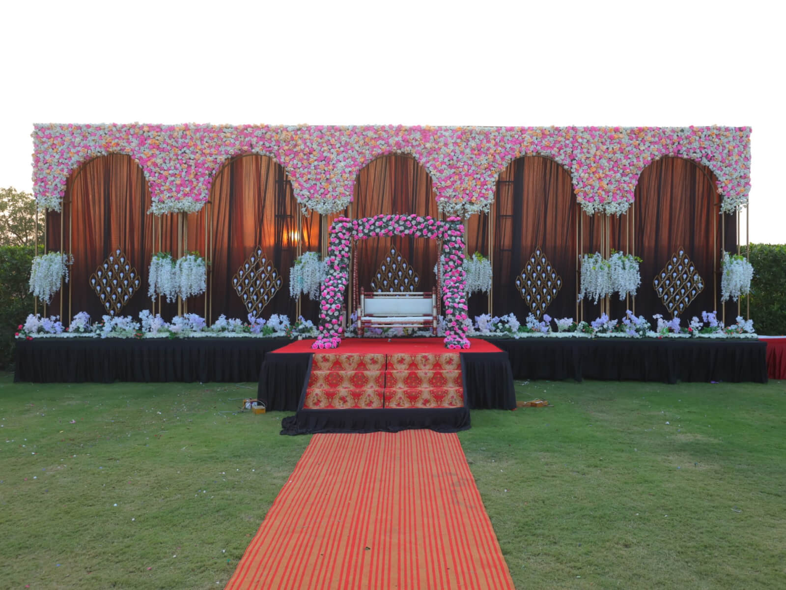 Outdoor wedding stage with floral arches, a swing, and elegant decorations, ideal for wedding ceremonies and special events.