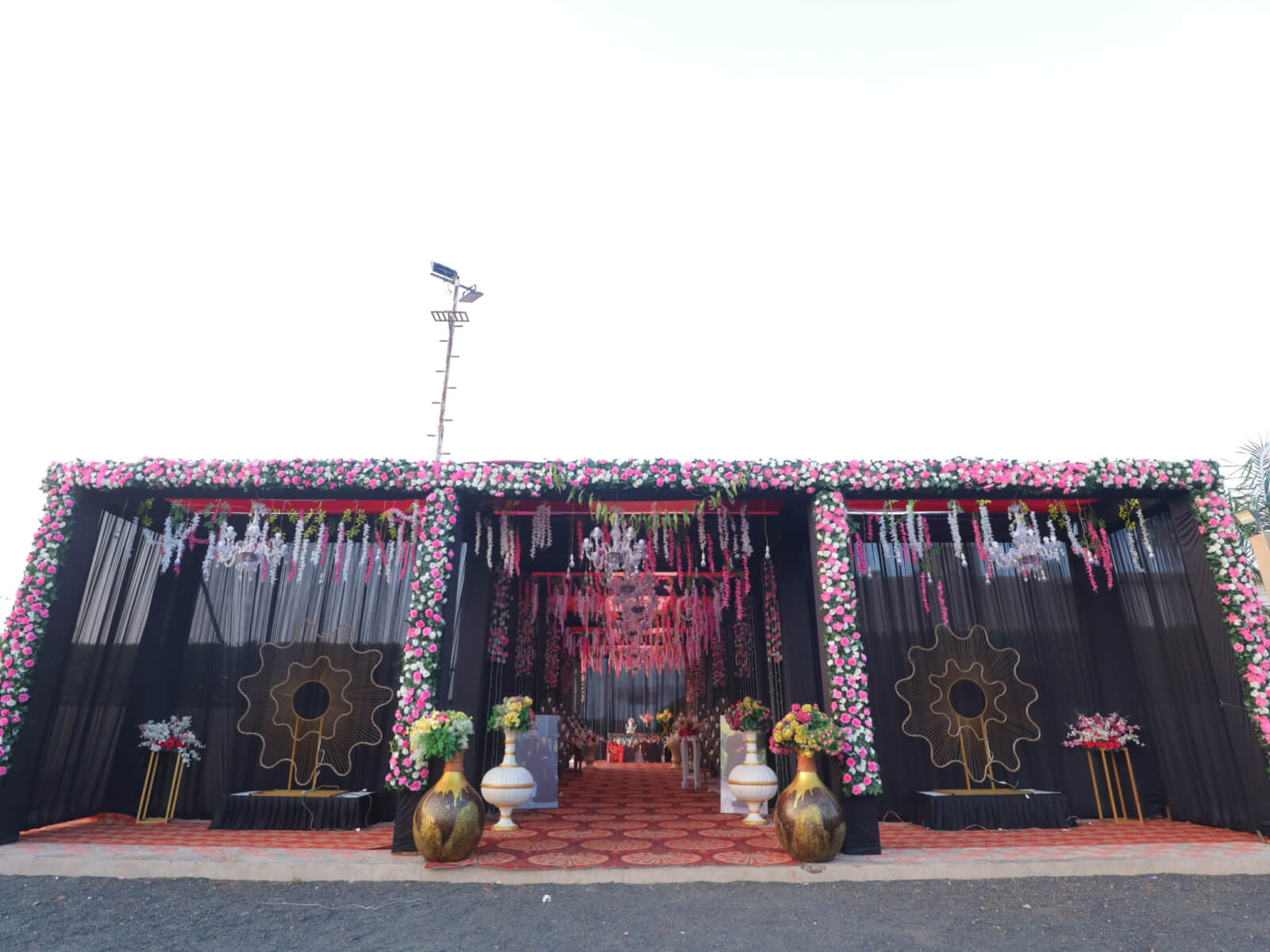 Indoor event Entrance with floral decorations, chandeliers, and couple portraits, ideal for wedding receptions and romantic celebrations.