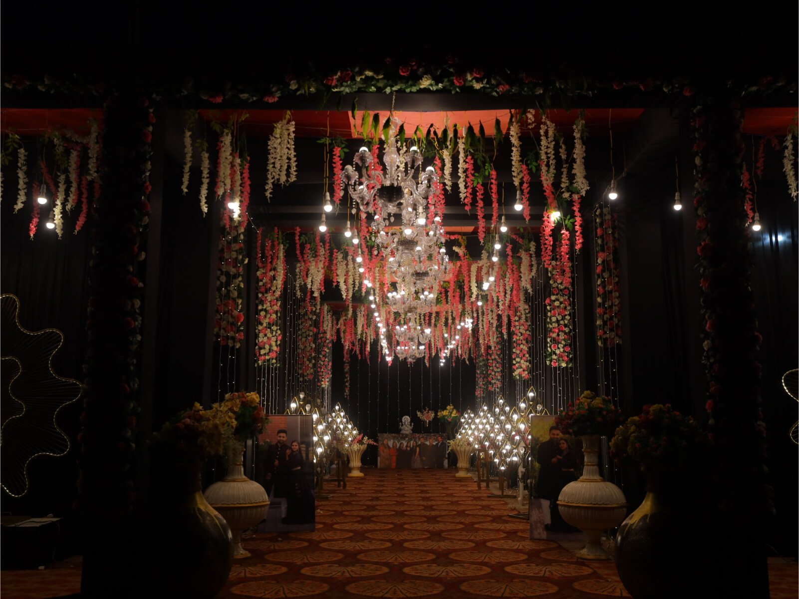 Indoor event hallway with floral decorations, chandeliers, and romantic lighting, ideal for wedding receptions and special celebrations.