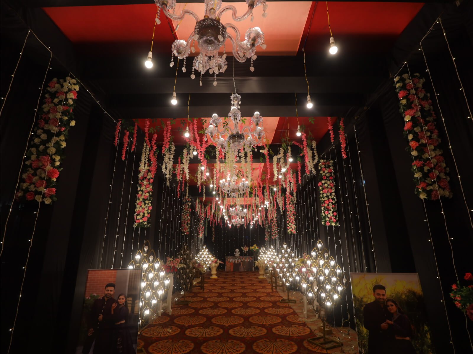 Indoor event hallway with floral decorations, chandeliers, and romantic lighting, ideal for wedding receptions and special celebrations.