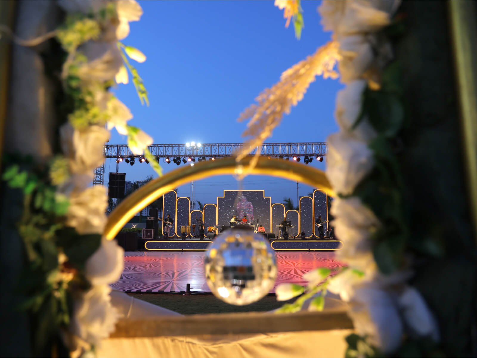 Indoor sangeet event decoration with vibrant drapes, colorful lighting, and floral arrangements, perfect for wedding celebrations and event planning.