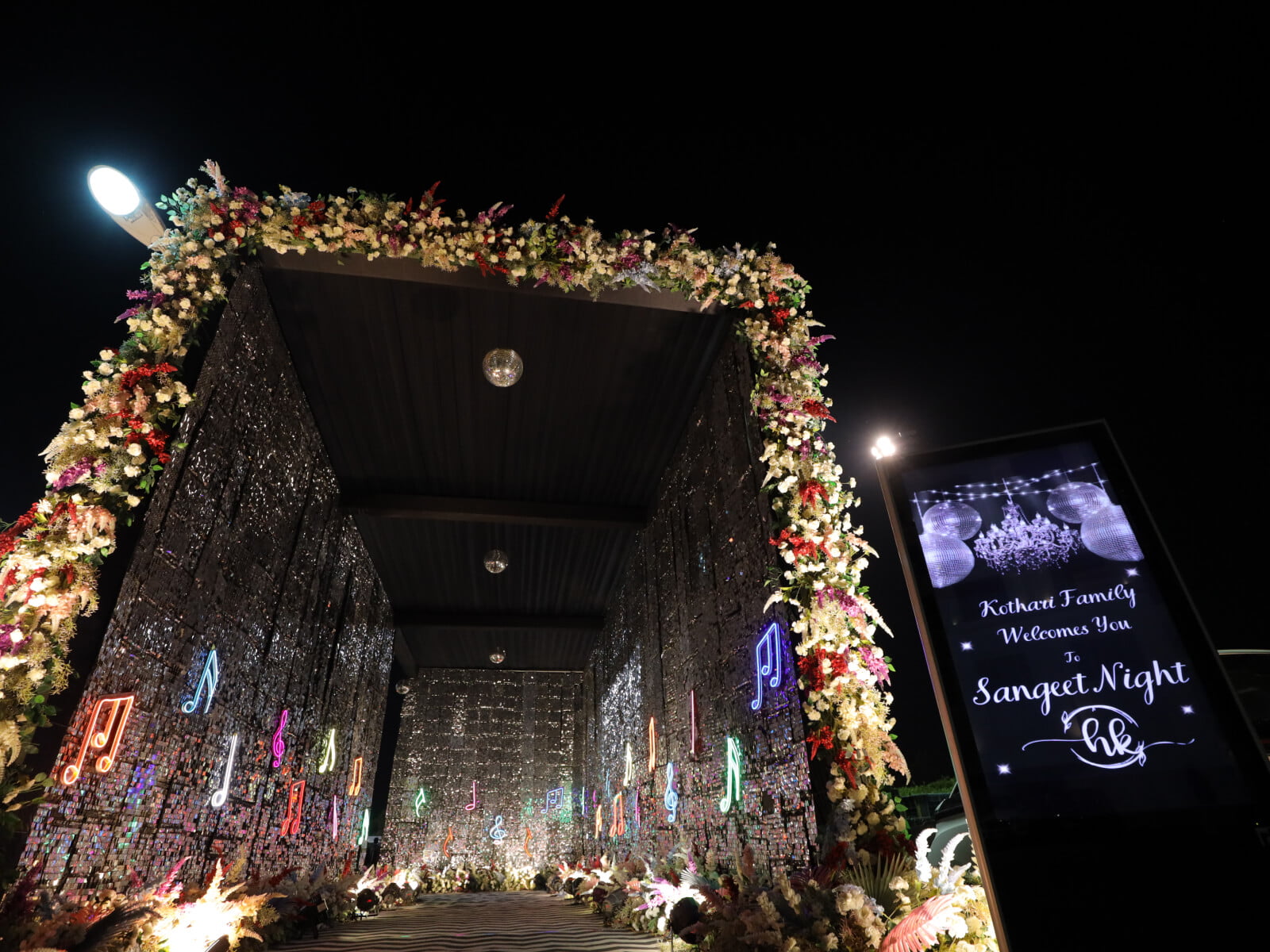 Indoor event backdrop Entrance with illuminated musical notes and floral arrangements, perfect for sangeet ceremonies and musical-themed celebrations.