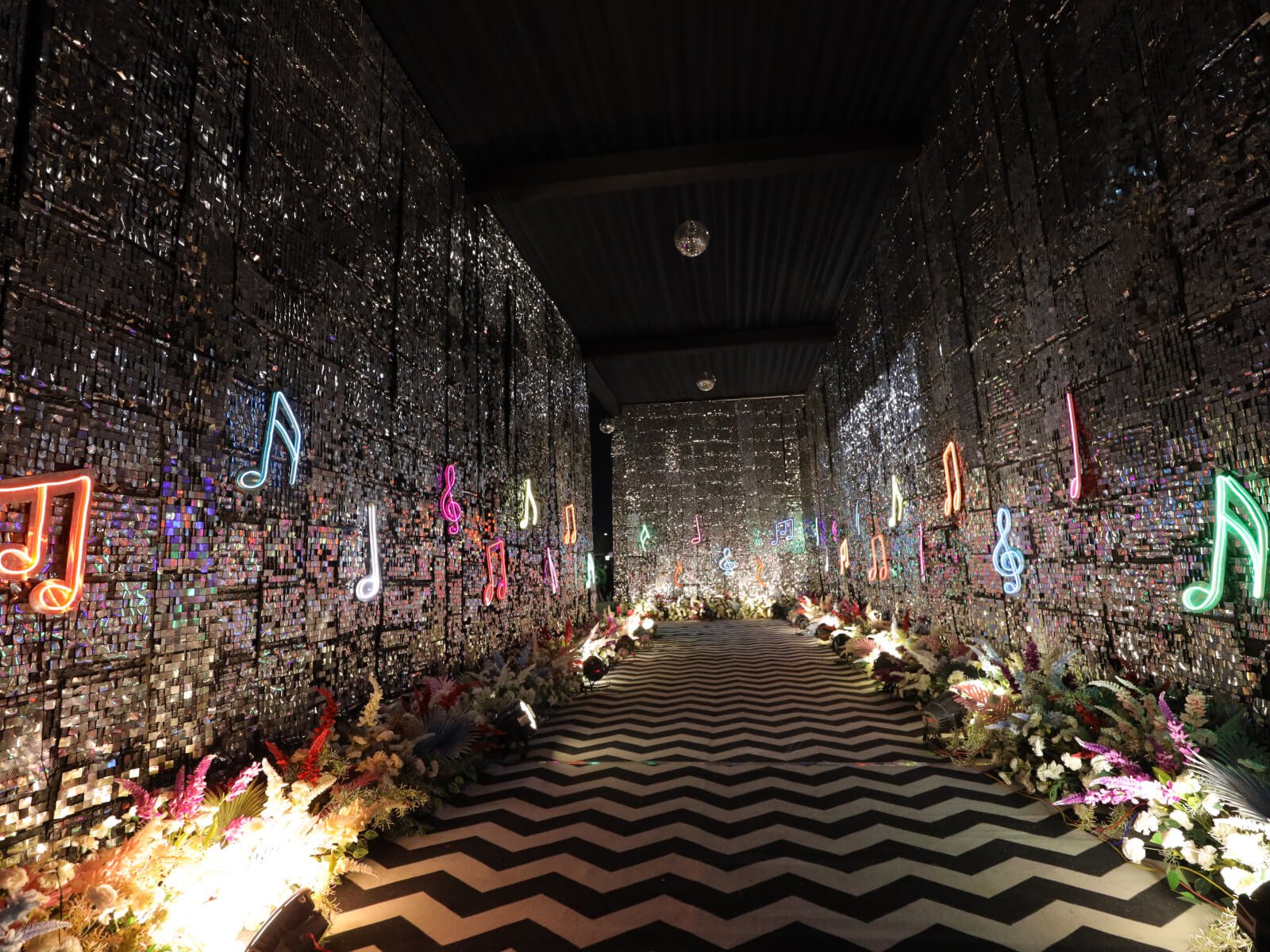 Indoor event backdrop Entrance with illuminated musical notes and floral arrangements, perfect for sangeet ceremonies and musical-themed celebrations.