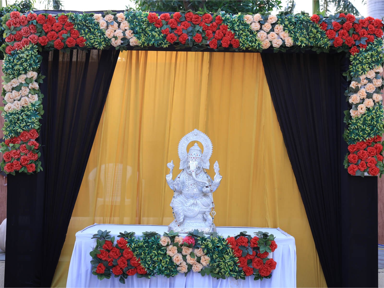 Outdoor event decoration with Ganesha idol and floral arrangements.