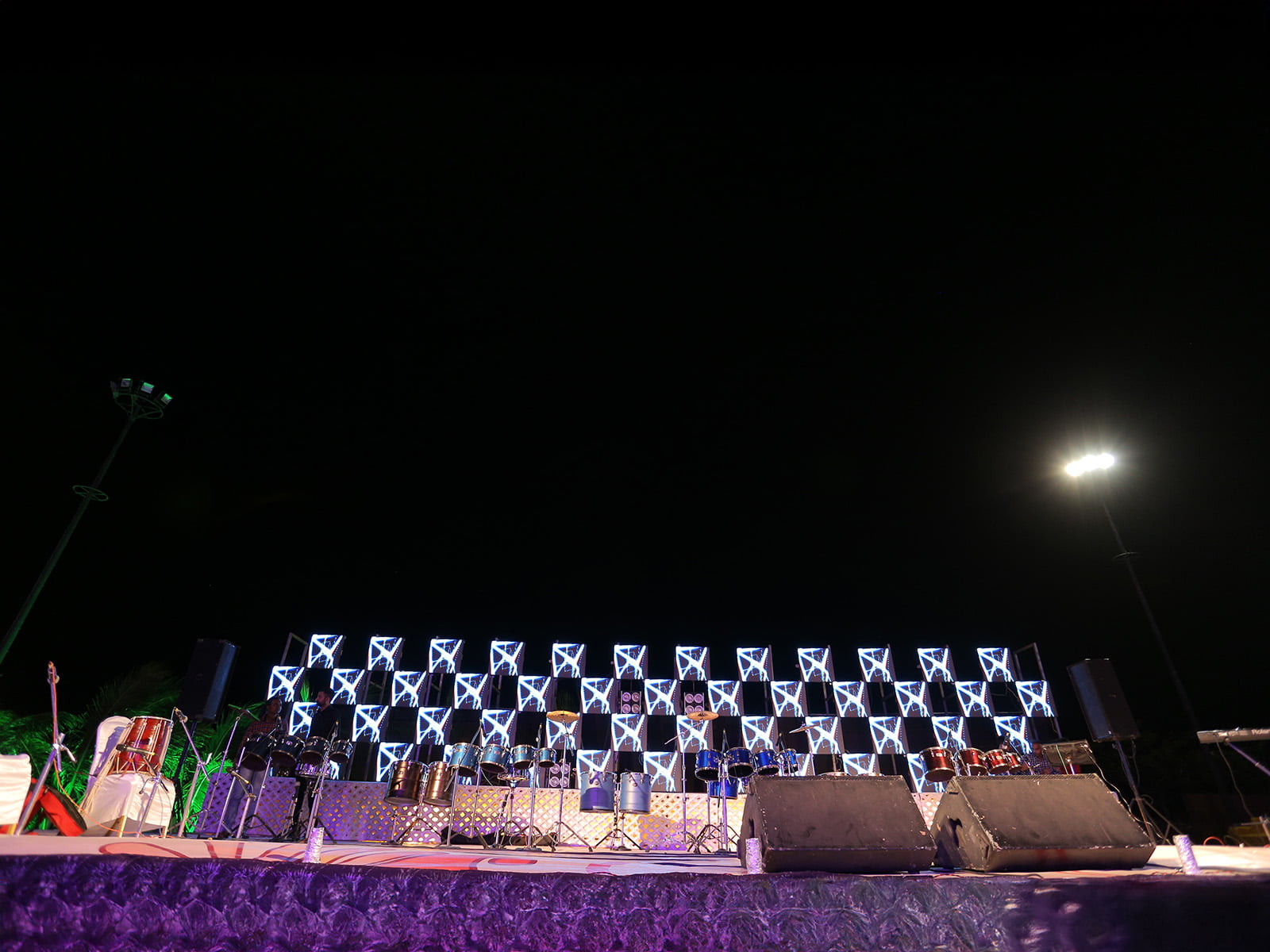 Outdoor event stage setup with musical instruments and illuminated backdrop, ideal for sangeet ceremonies, event planning, and wedding decoration.