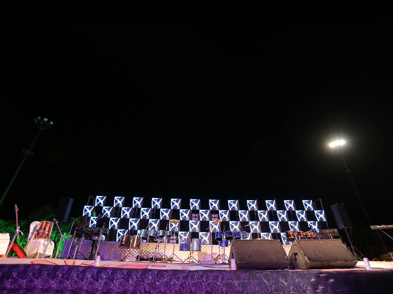 Outdoor event stage setup with musical instruments and illuminated backdrop, ideal for sangeet ceremonies, event planning, and wedding decoration.