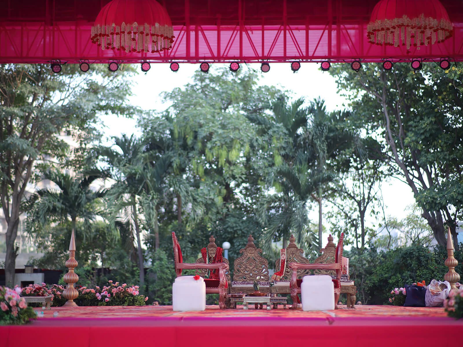 Outdoor wedding mandap with traditional chairs, floral decorations, and ceremonial setup.