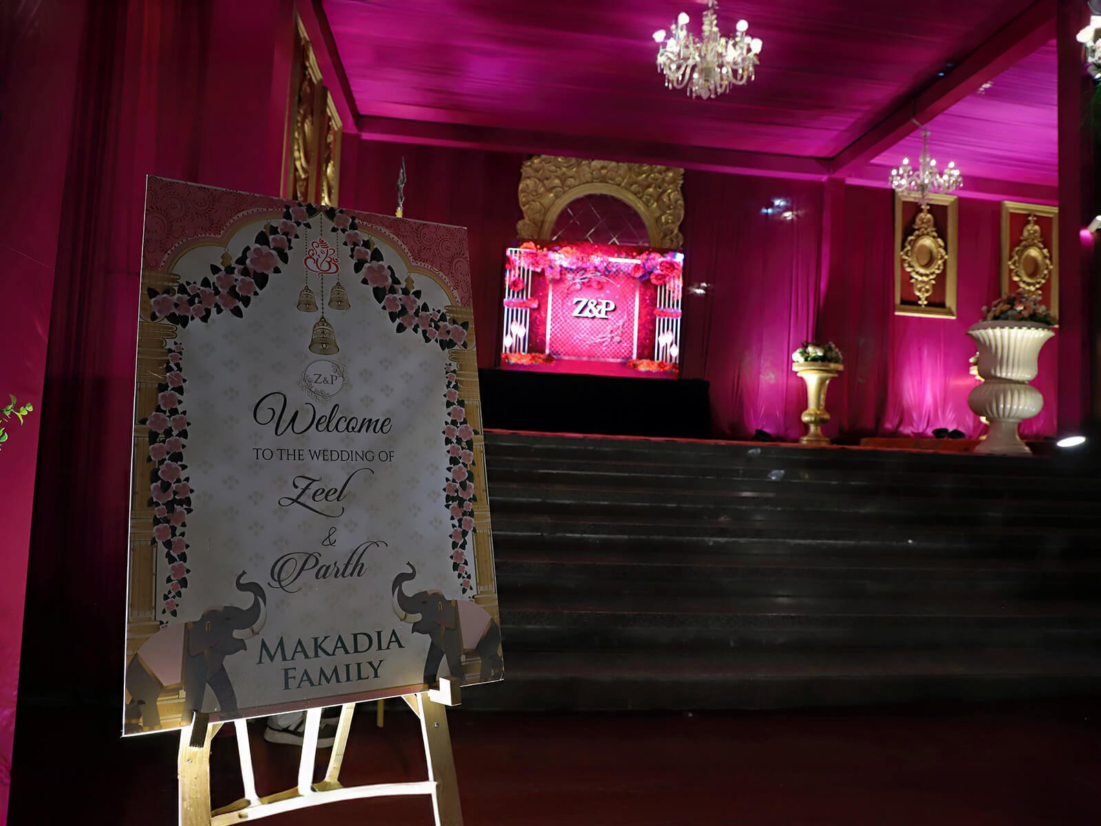 Indoor wedding entrance with vibrant drapes, floral arrangements, and elegant lighting.