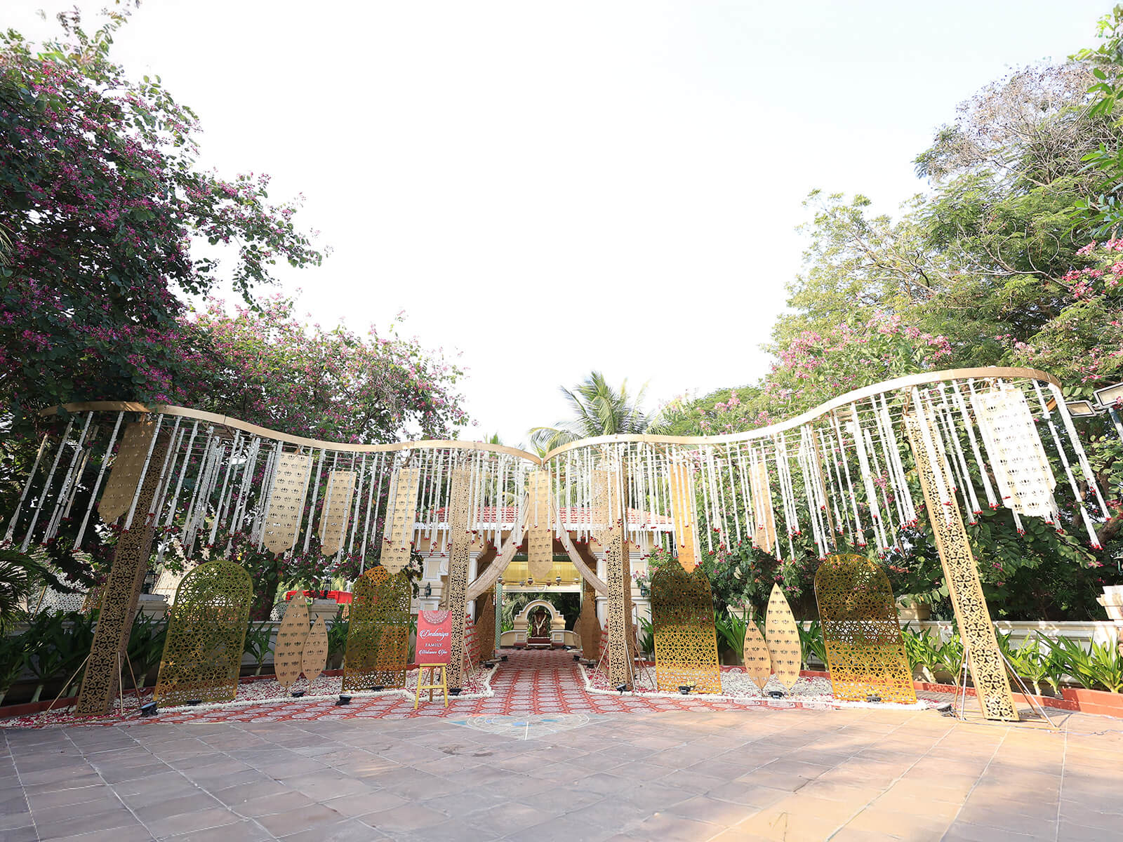 Outdoor wedding event decoration with intricate golden panels, floral arrangements, and elegant canopy, ideal for destination weddings and event planning.