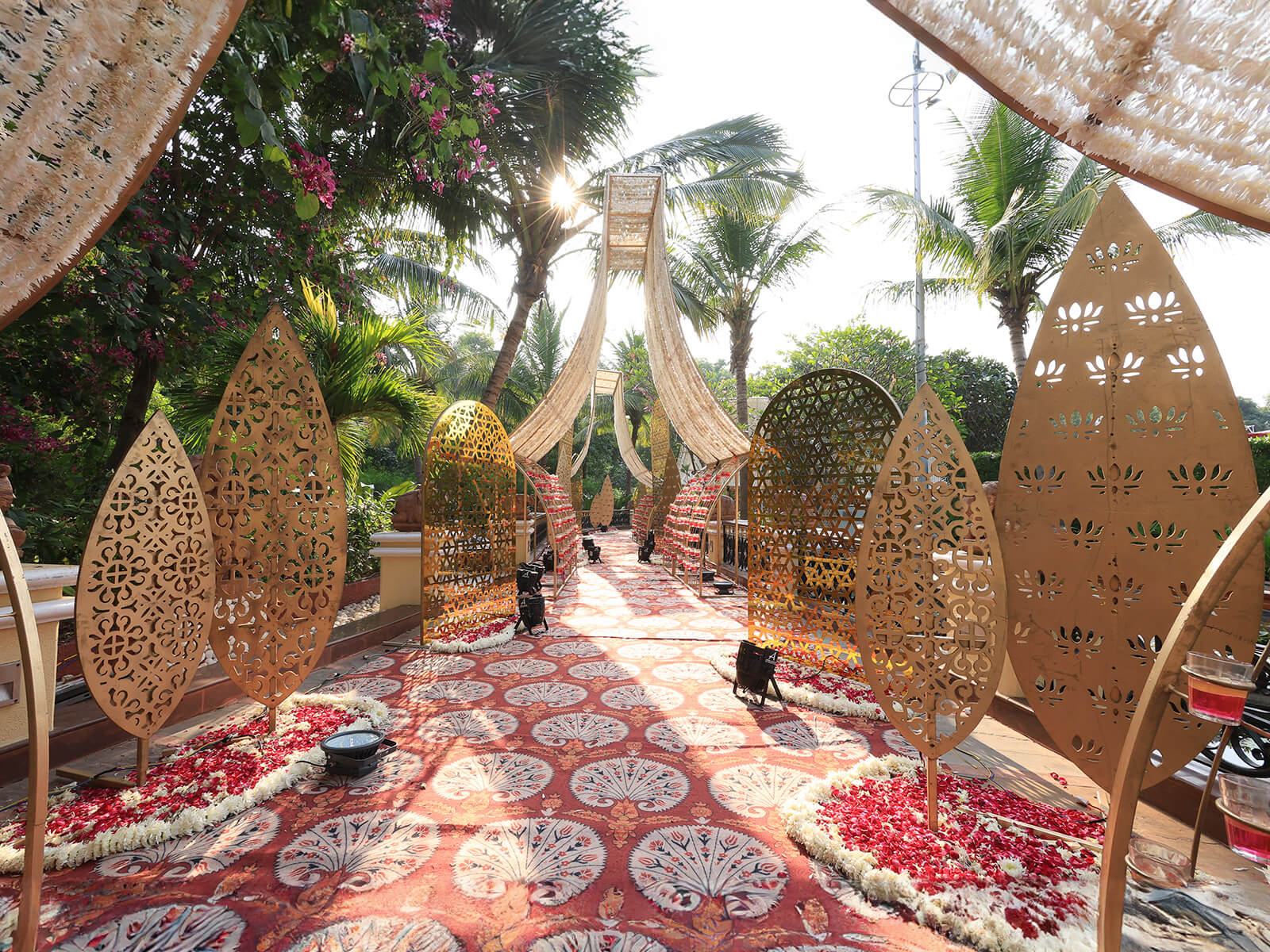 Outdoor wedding event decoration with intricate golden panels, floral arrangements, and elegant canopy, ideal for destination weddings and event planning