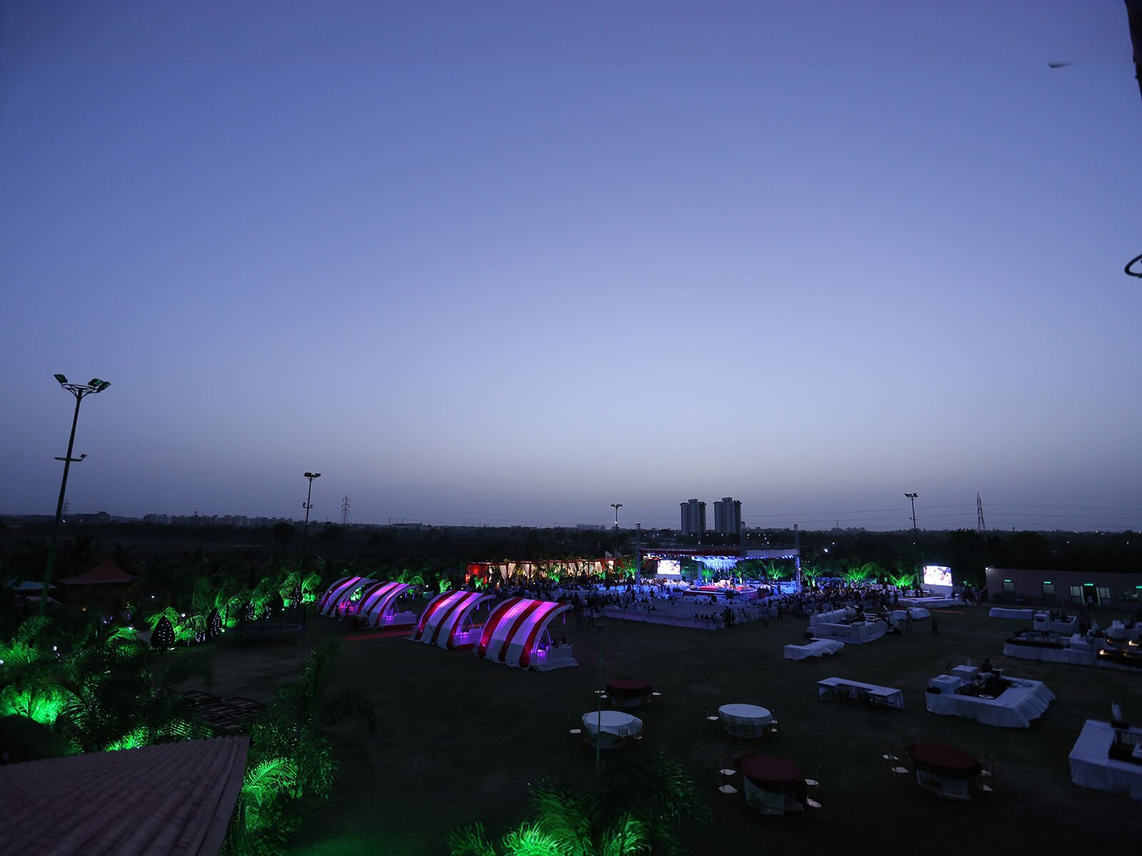 Outdoor wedding event at dusk with illuminated tents and seating arrangements.